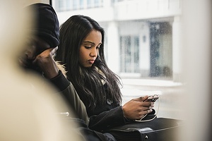 A woman checks her phone on the bus