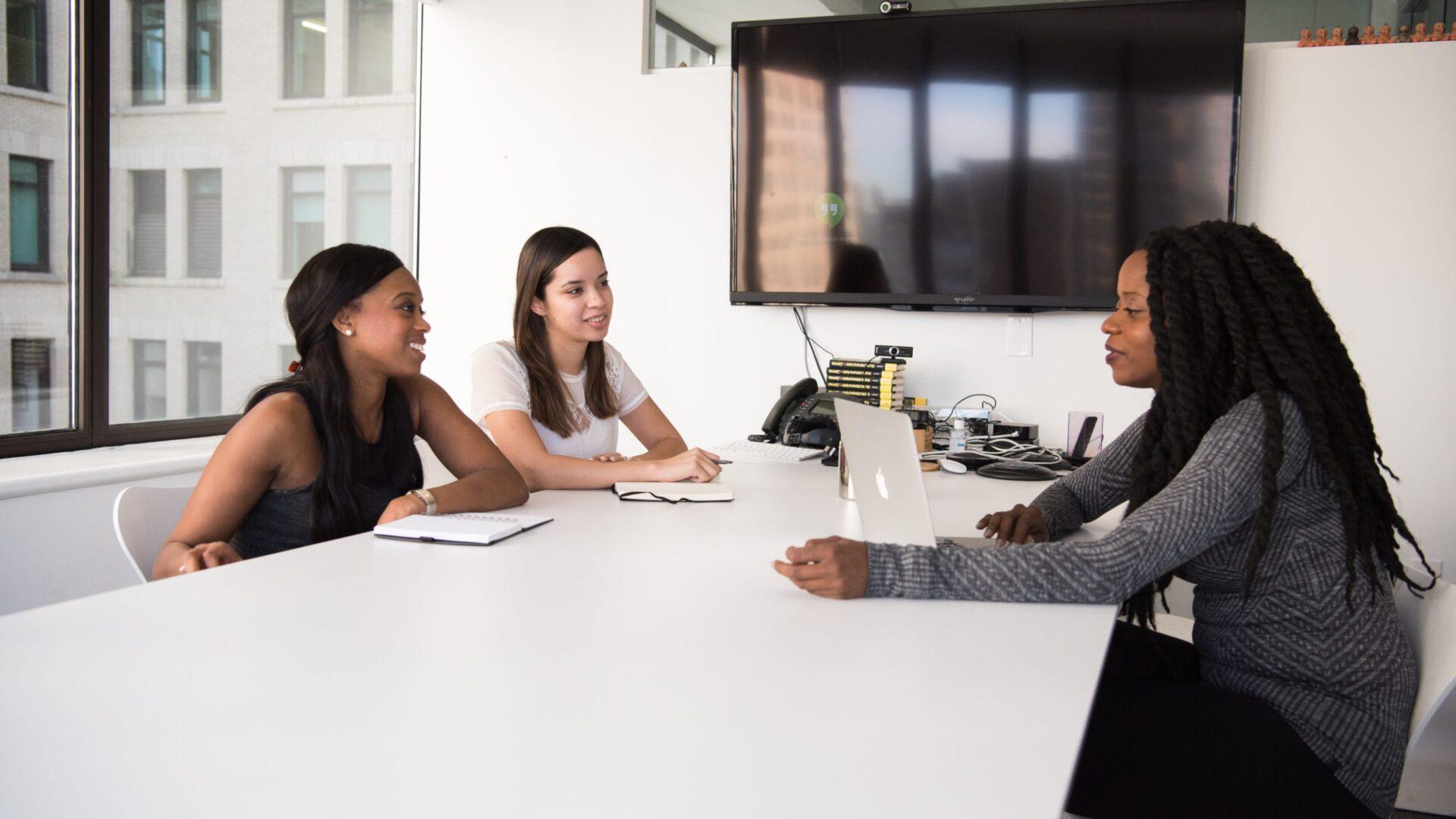 Three women having a meeting in a conference room.