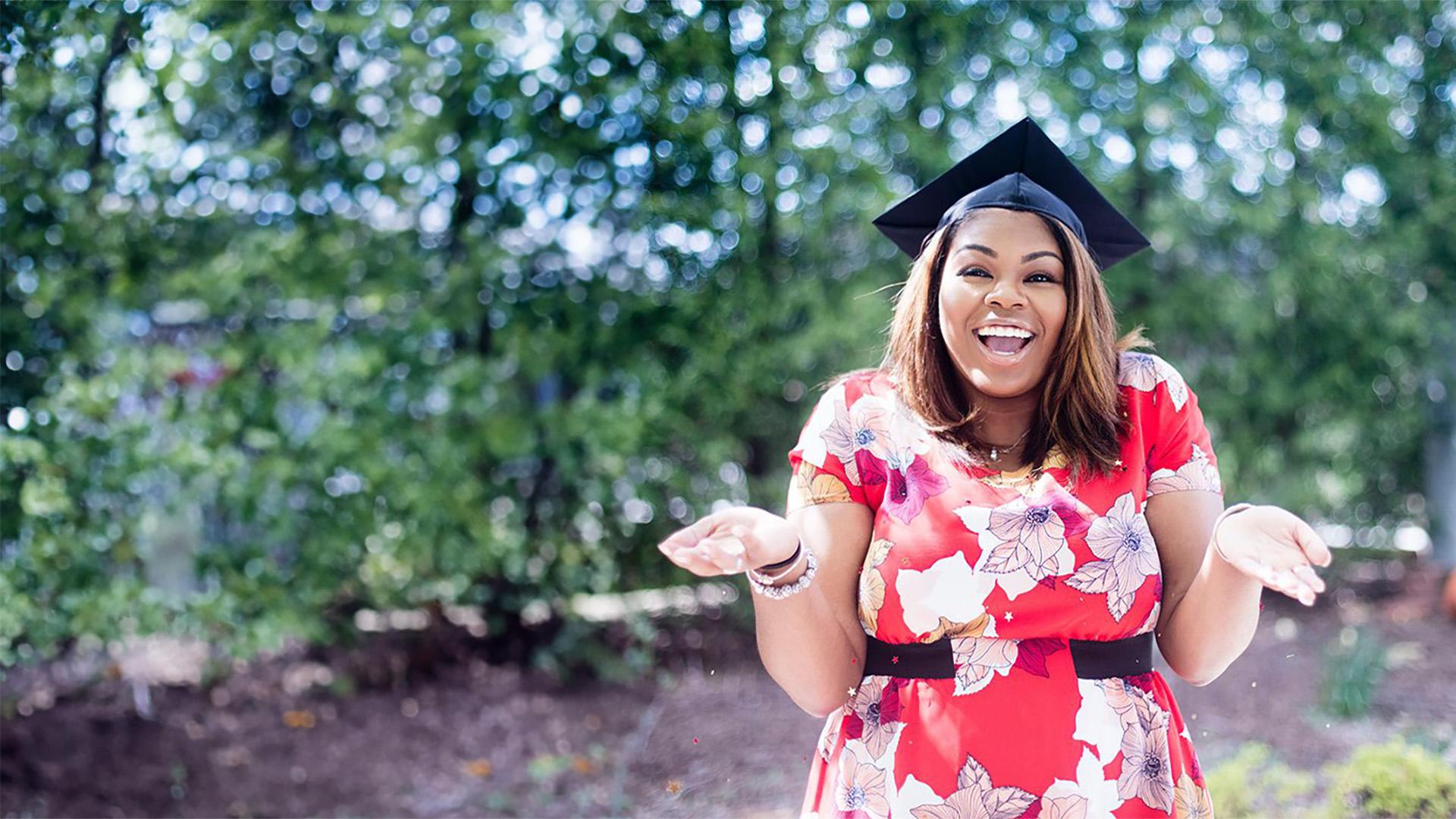 A happy student wearing a mortarboard cap poses for the camera.