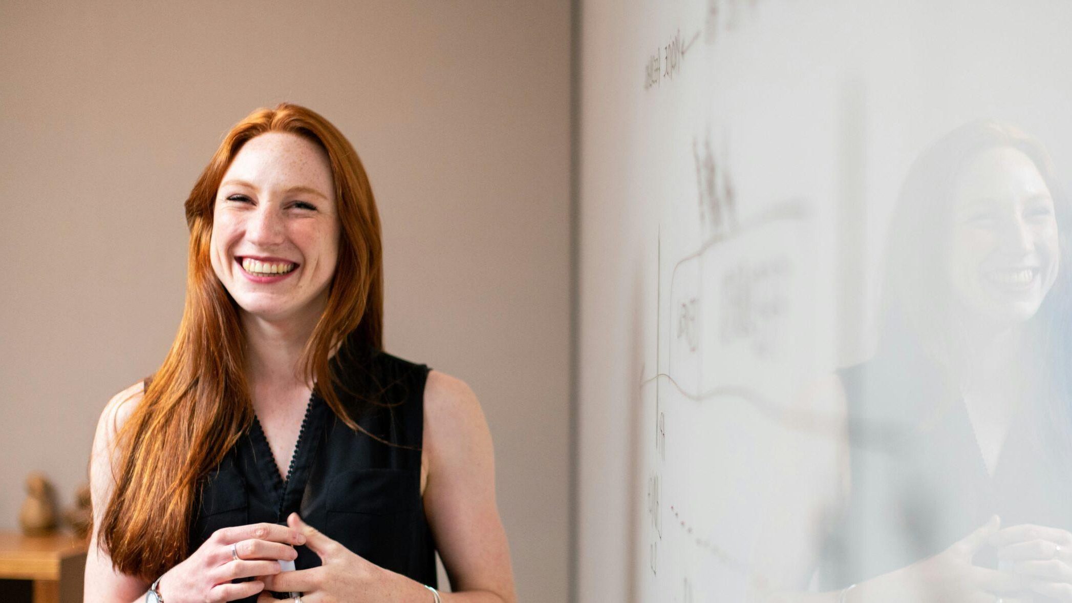 A smiling student standing in front of a whiteboard.