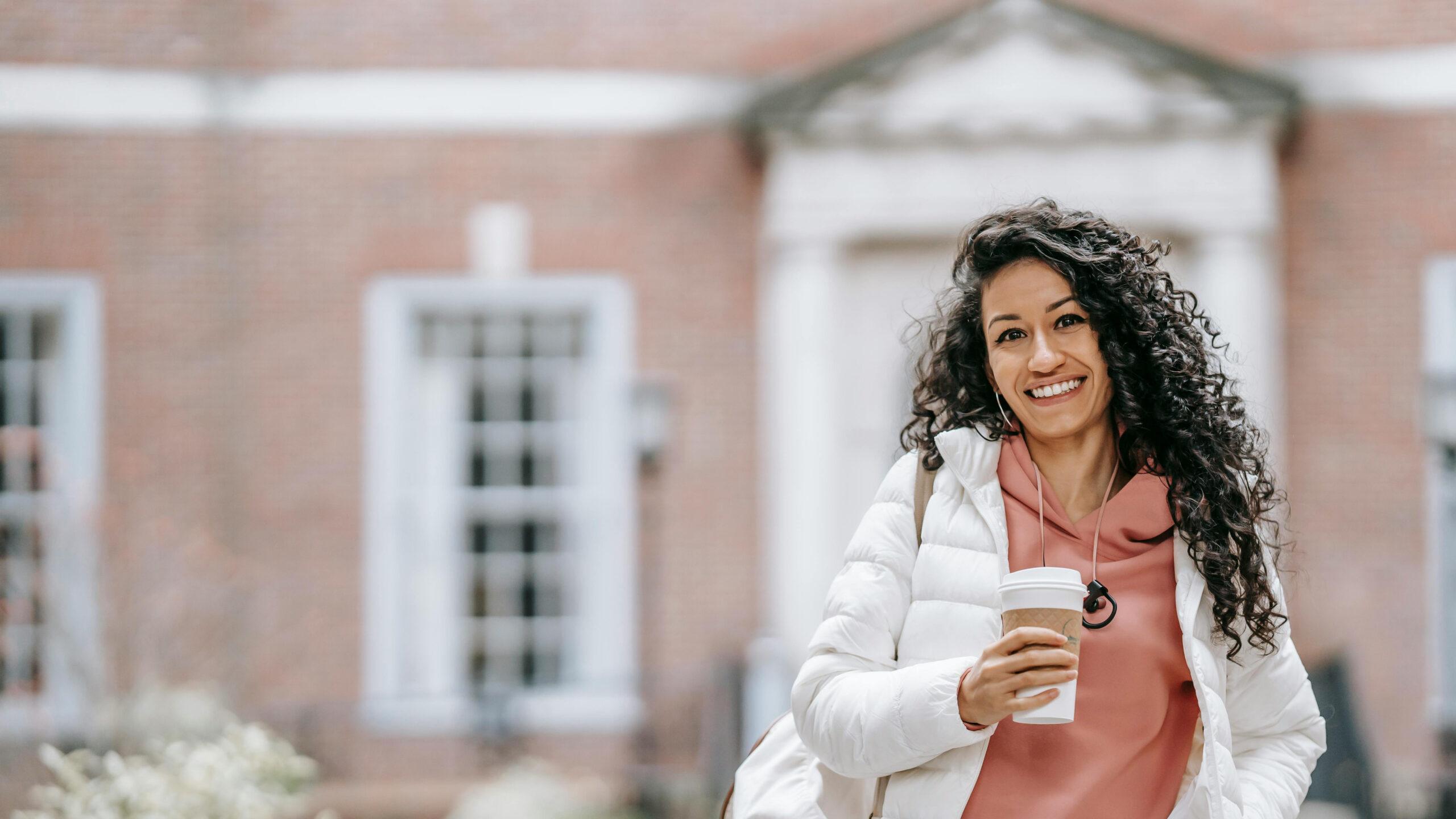 A confident student holding a coffee.