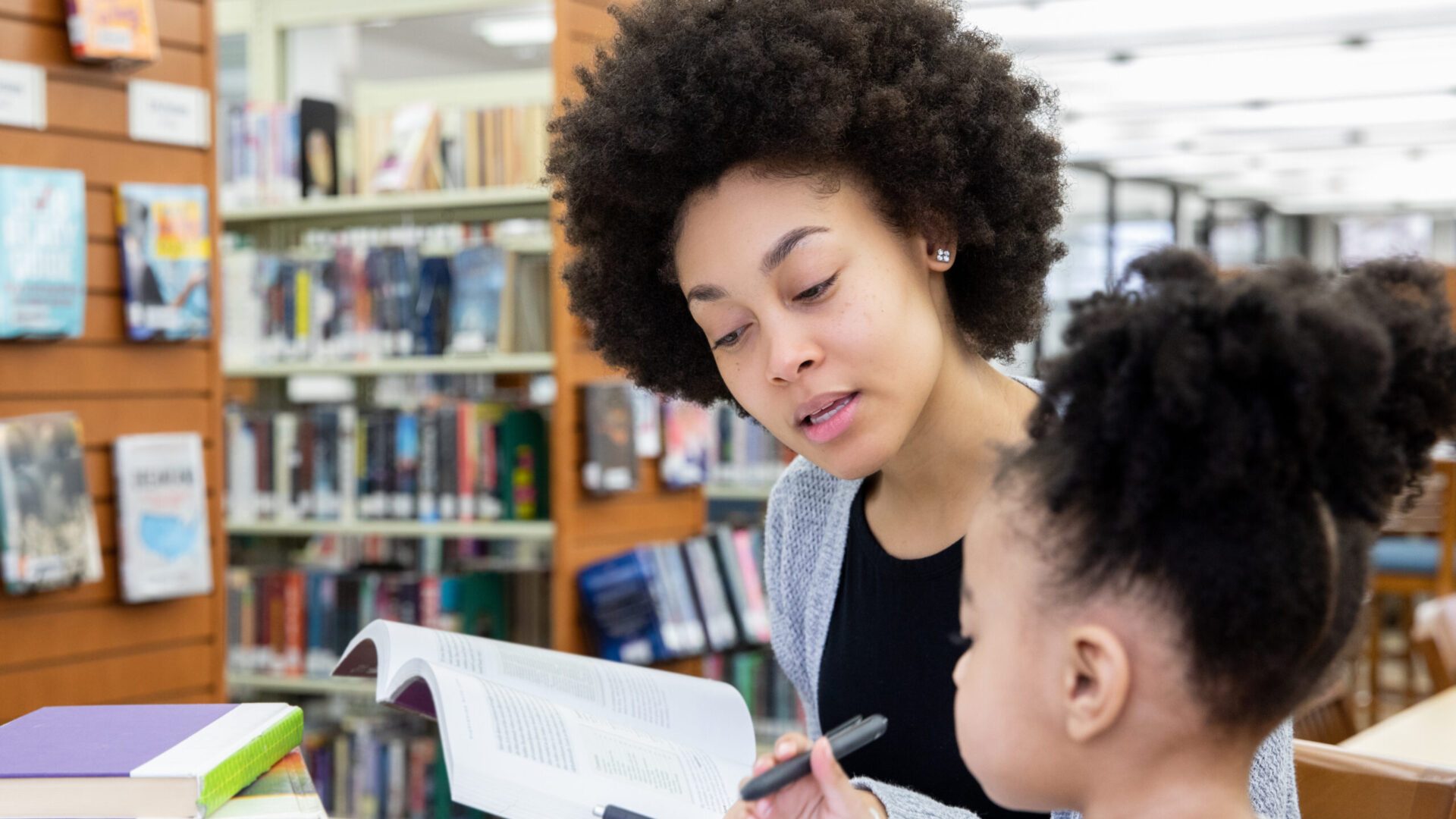 Student mother studies in library with toddler daughter.