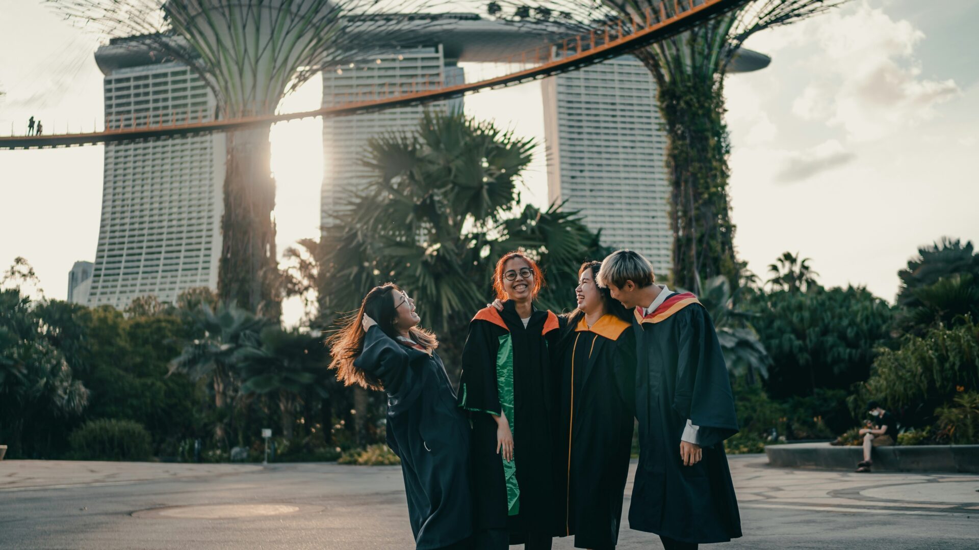 A group of students in graduation gowns pose together in front of modern sculptures.