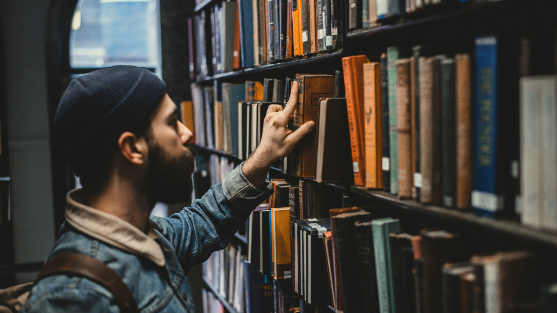 A student browsing through the books in a library.