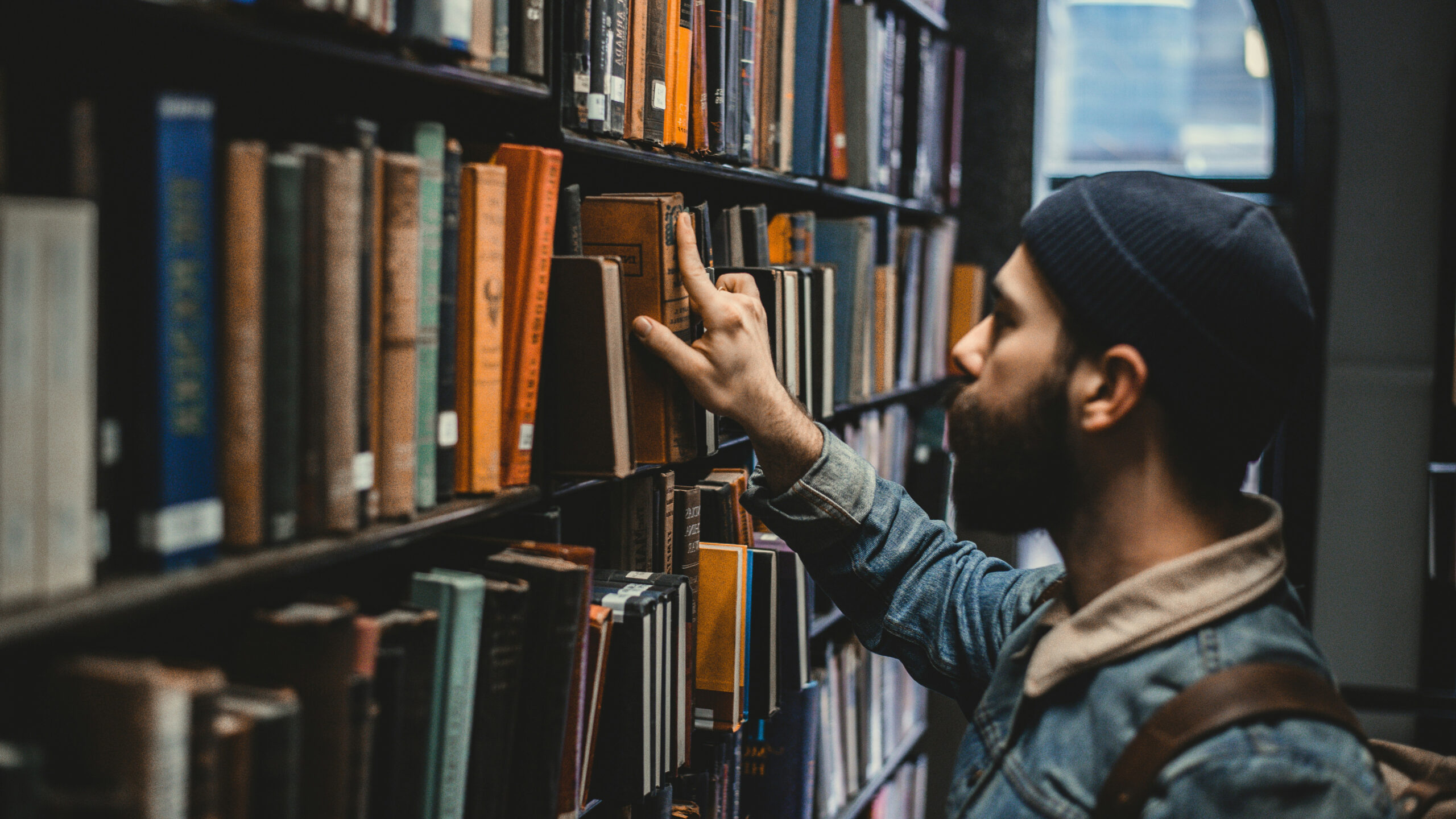 A student browsing through the books in a library.