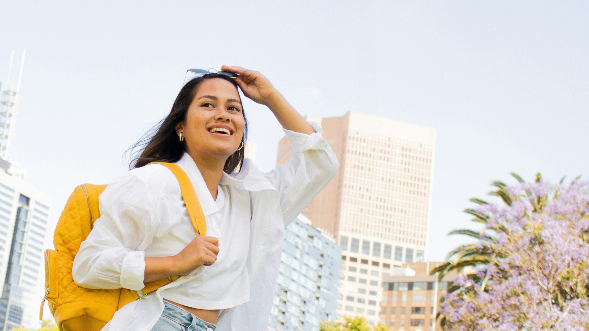 Happy student with backpack walking through city campus.