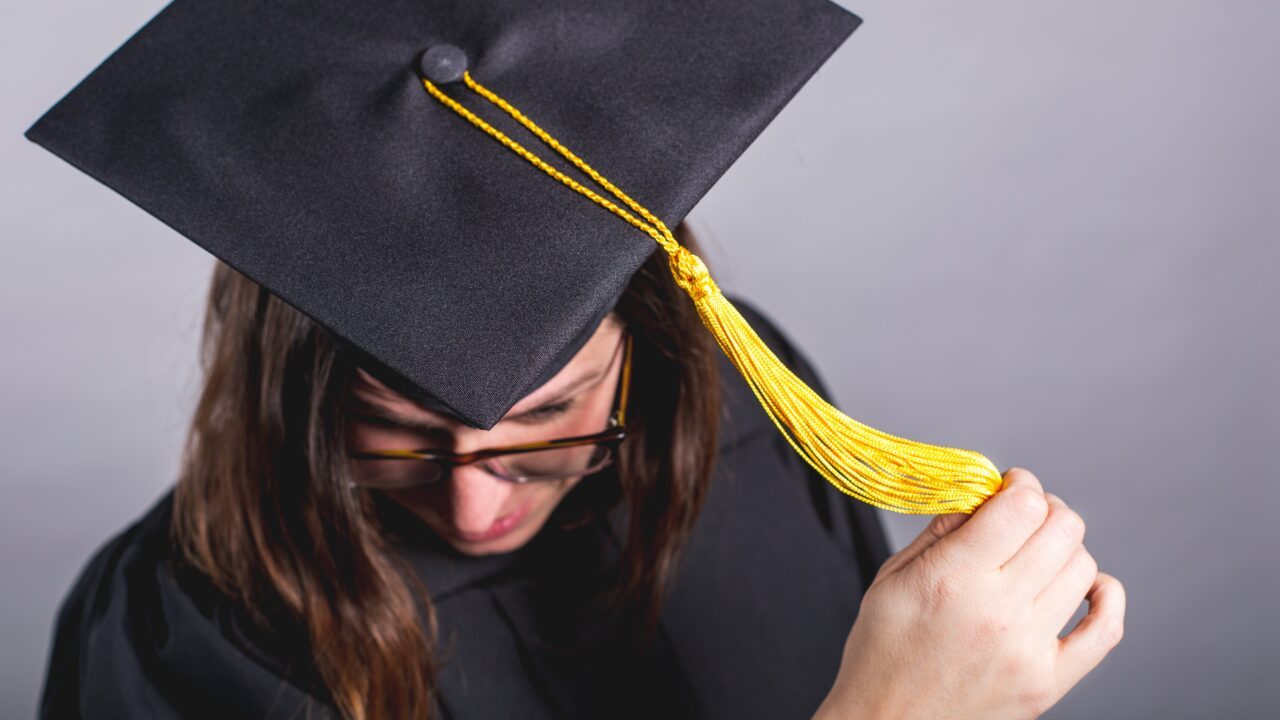 A student moving the tassel on her mortarboard cap.