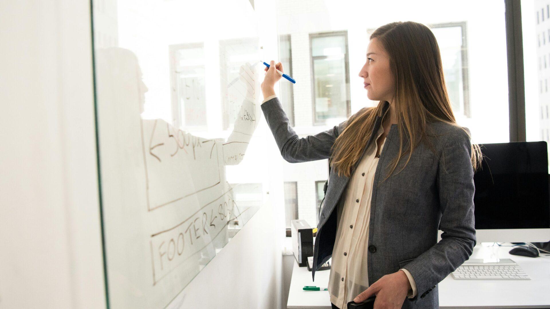 A woman writing on a whiteboard.