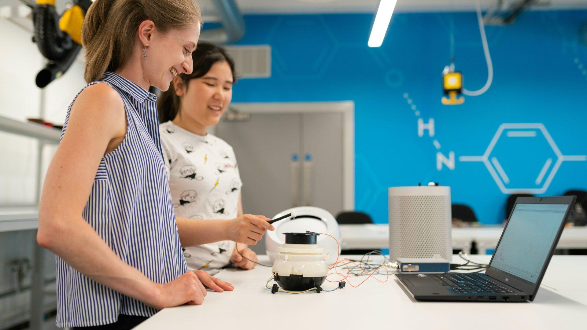 two women in an engineering classroom a laptop and engineering equipment for a project