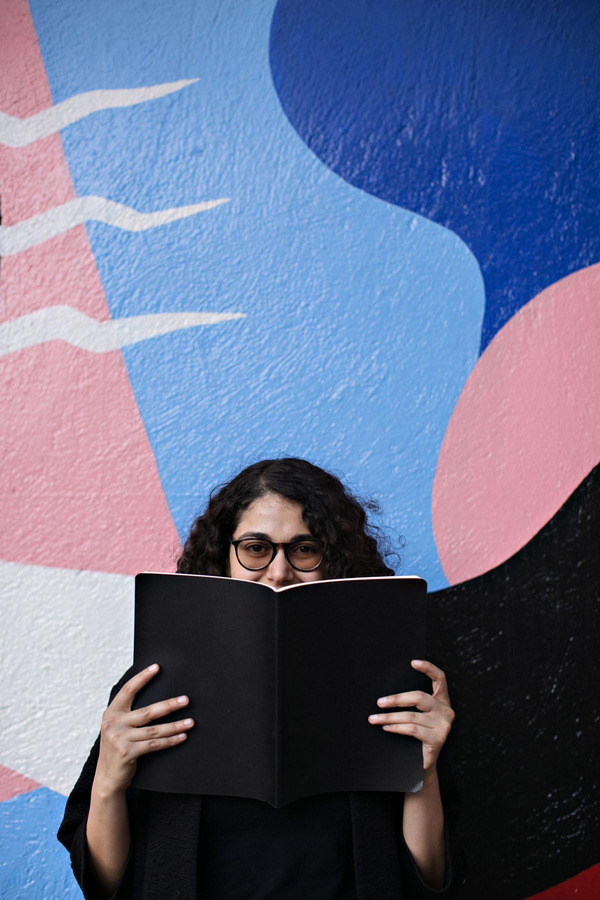 young woman reading a book against a colorful wall