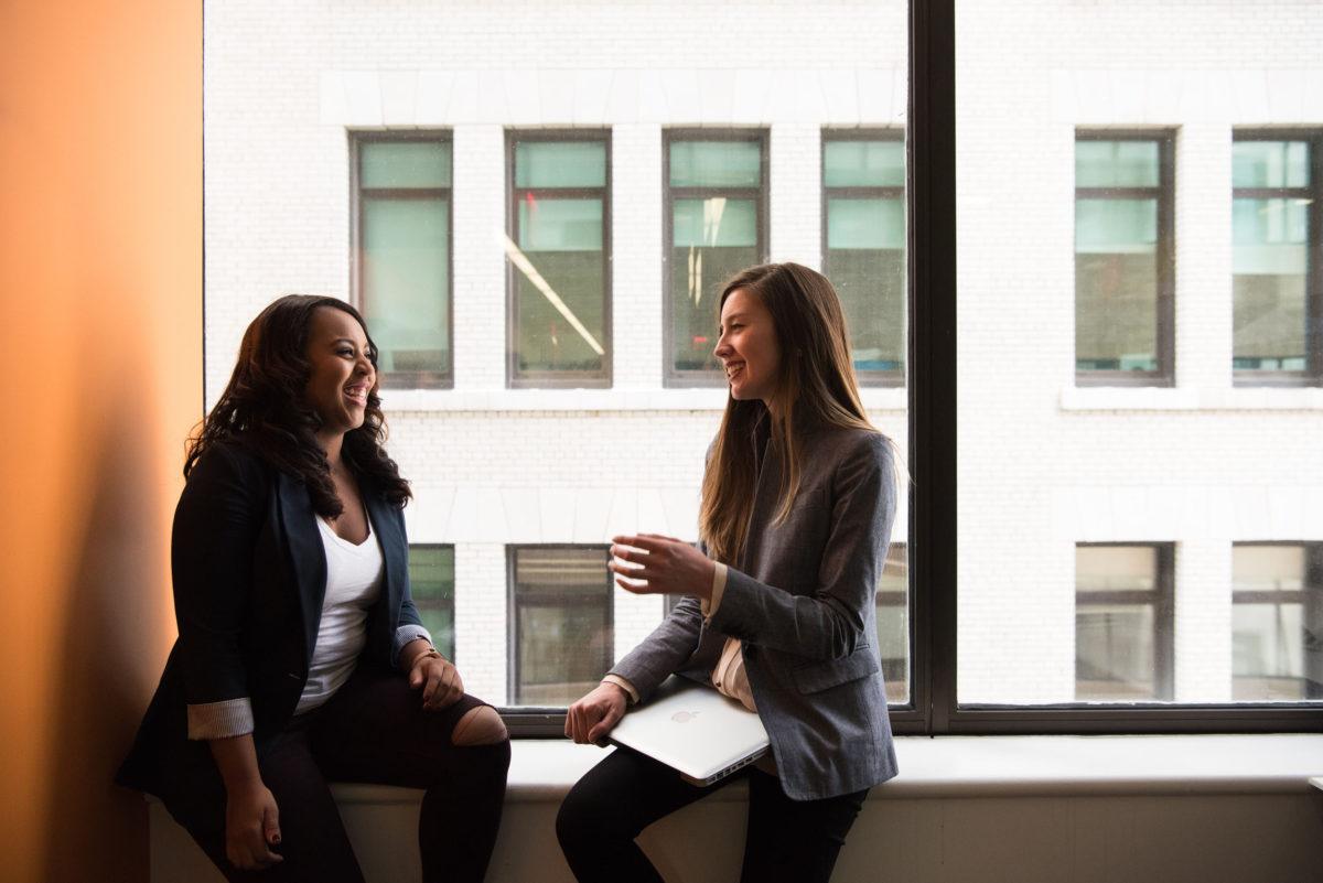 two young women talking in a window