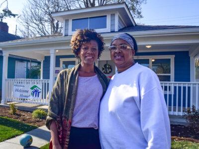 Two women stand outside their new home built by Habitat for Humanity