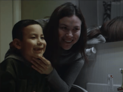 A single mom looks in the mirror with her son who has just lost a tooth