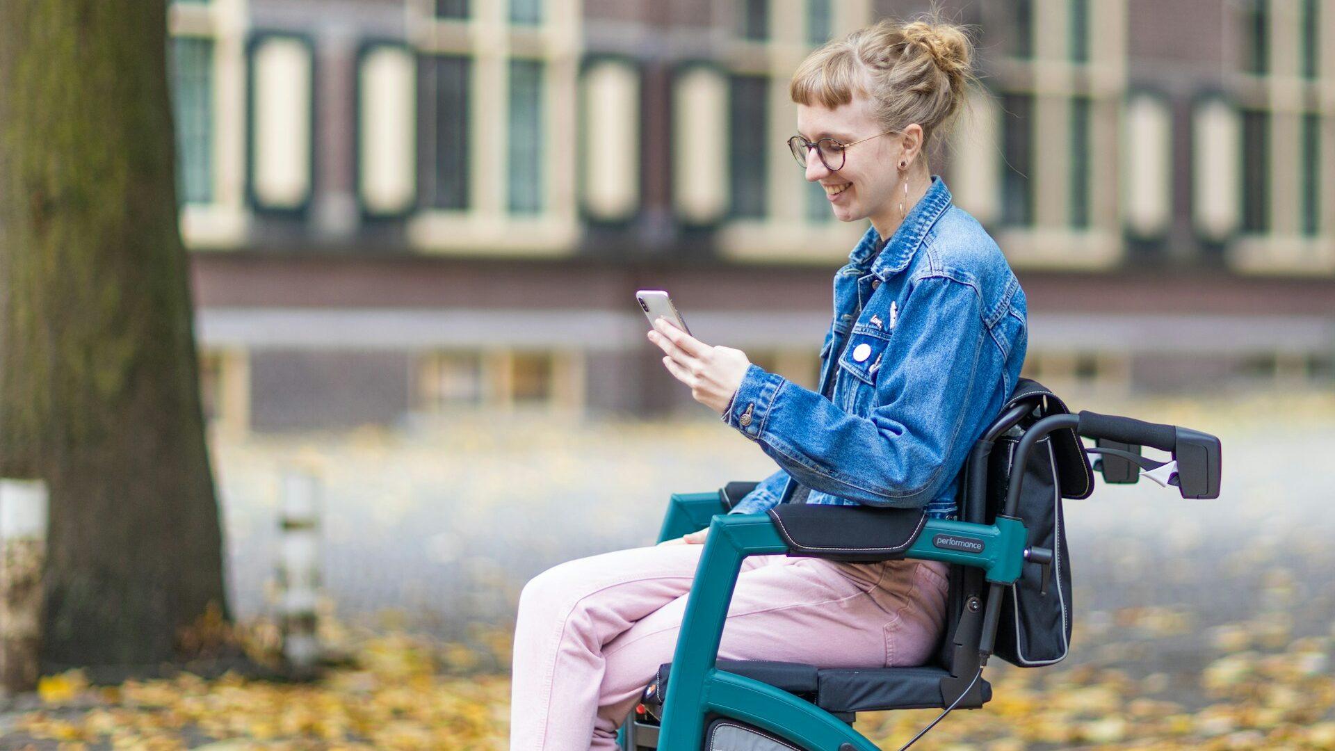 A woman sitting in an electric mobility chair and using a cell phone on a college campus