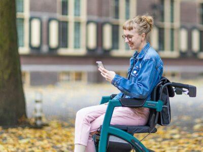 A woman sitting in an electric mobility chair and using a cell phone on a college campus