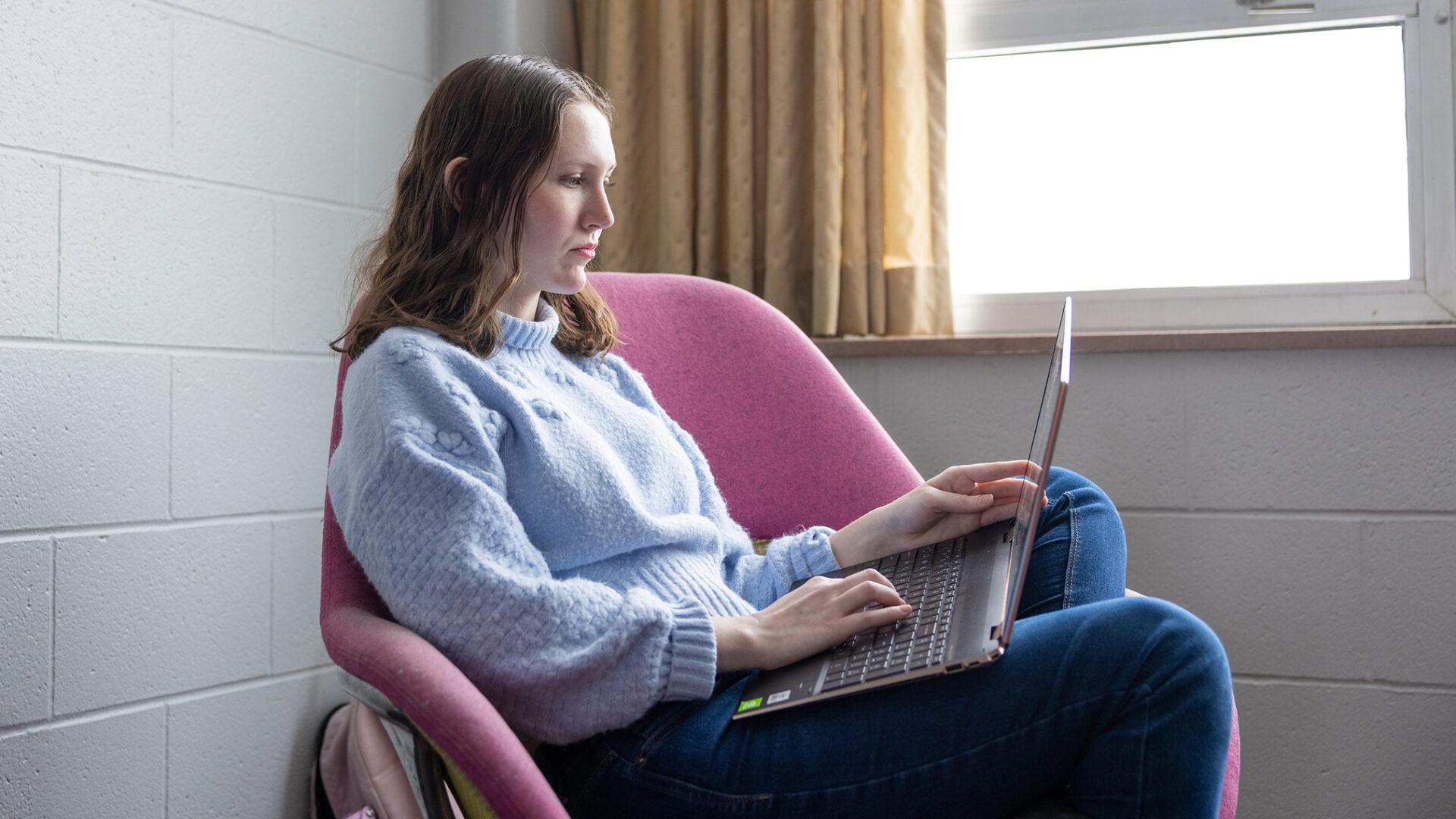 Female student studying in a residence hall common area on a college campus.