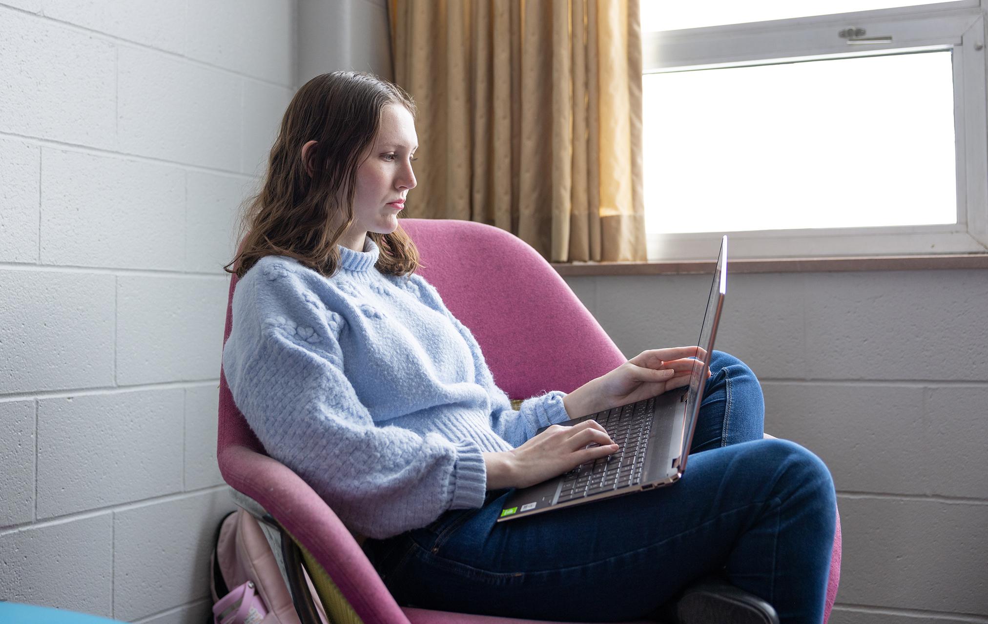 Female student studying in a residence hall common area on a college campus.